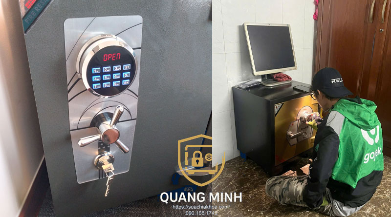 Bên trái mặt két xám có bàn phím tròn hiện chữ OPEN, tay gạt và ổ chìa; bên phải thợ áo xanh ngồi cạnh két đặt dưới máy tính