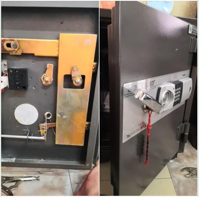 Mặt trong cánh két tháo tấm che, lộ hộp khóa điện màu đen, lẫy vàng và dây đỏ, cạnh đó là két điện tử đã mở cửa