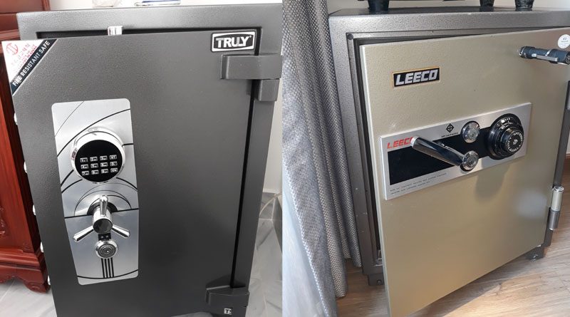 Két sắt Truly màu đen có bàn phím số tròn và tay gạt ba chấu, bên cạnh là một két cơ hãng khác